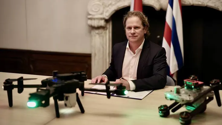 Staatssecretaris Tuinman zit achter de tafel waar 2 drones op staan.