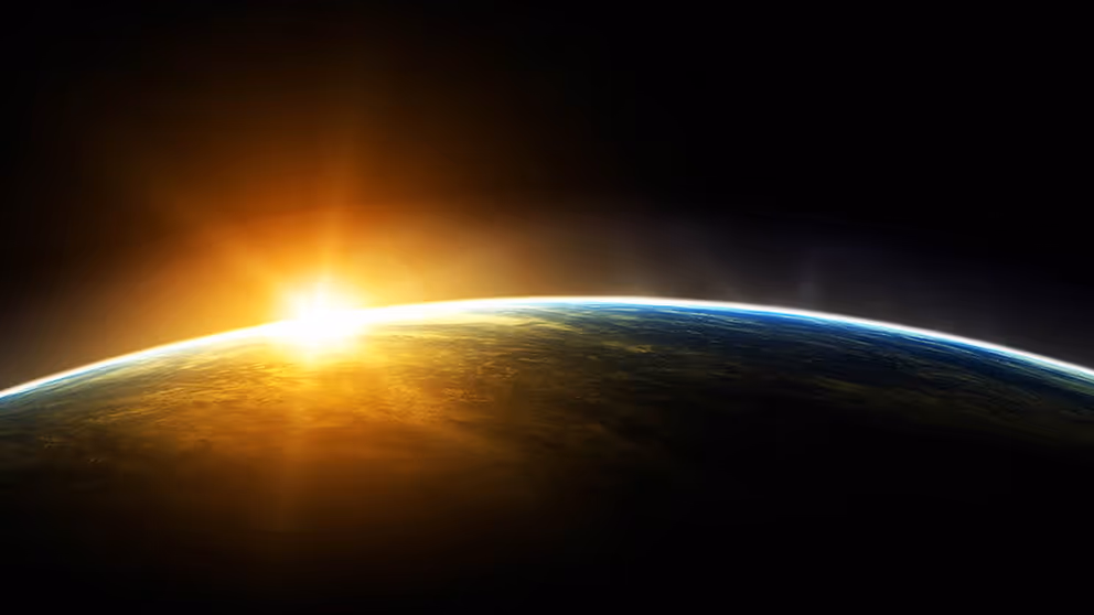 De aarde met een zonnestraal net boven de planeet, gezien vanuit de ruimte.