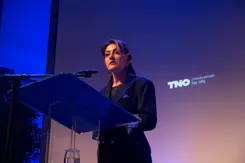 Minister Yeşilgöz staat achter het spreekgestoelte en houdt een speech.
