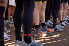 Benen van zo'n 10 sporters. Staan in groepje bij elkaar.