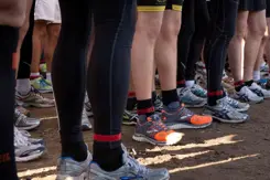 Benen van zo'n 10 sporters. Staan in groepje bij elkaar.