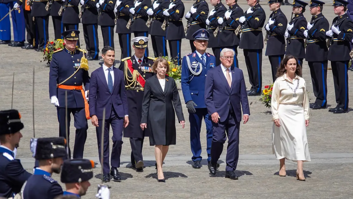 Minister-president Rob Jetten loopt samen met de bondspresident van Duitsland, diens vrouw en de burgemeester van Amsterdam door een erehaag van militairen gekleed in ceremonieel tenue. Vlak achter hen lopen ook drie militairen in ceremonieel tenue.
