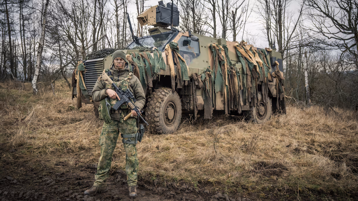 Militair poseert voor Bushmaster-pantserwielvoertuig