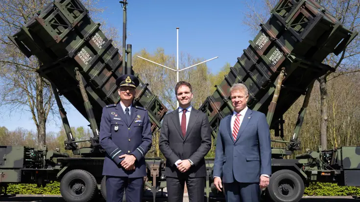 De staatssecretaris en 2 anderen staan voor een Patriot. 