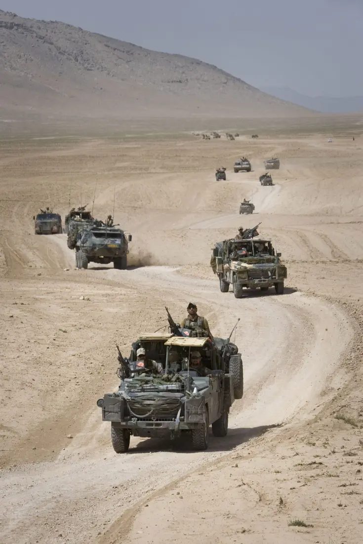 Militairen rijden door woestijn in Afghanistan.