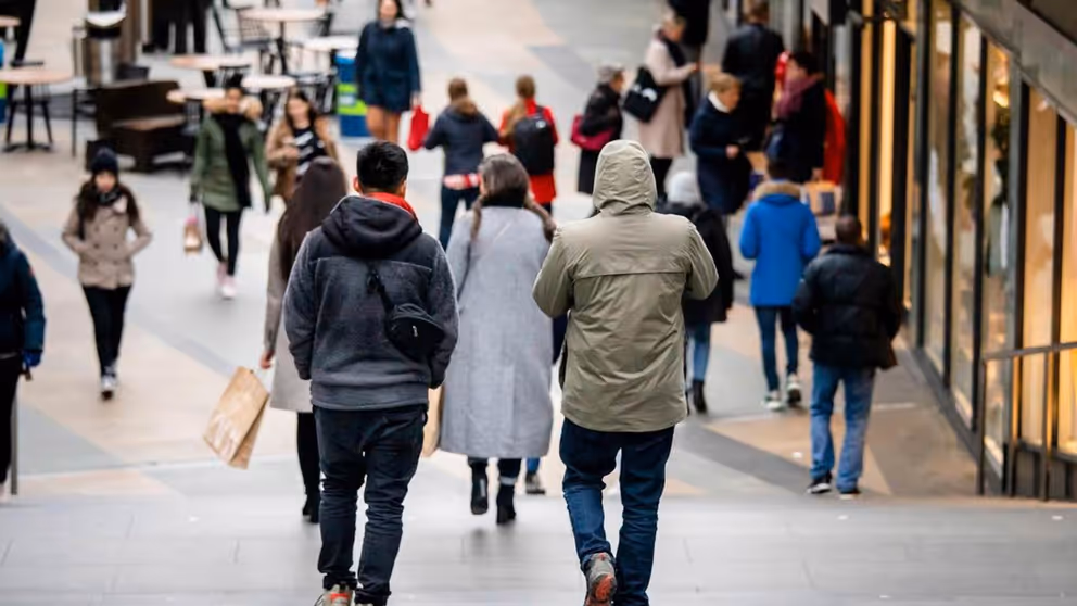 Ruggen van lopende mensen in een winkelstraat.