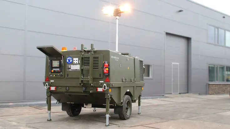Het legergroene systeem helikopterondersteuning staat voor een grijze loods.