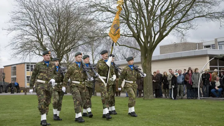 Militairen dragen het vaandel van het Regiment Infanterie Johan Willem Friso.