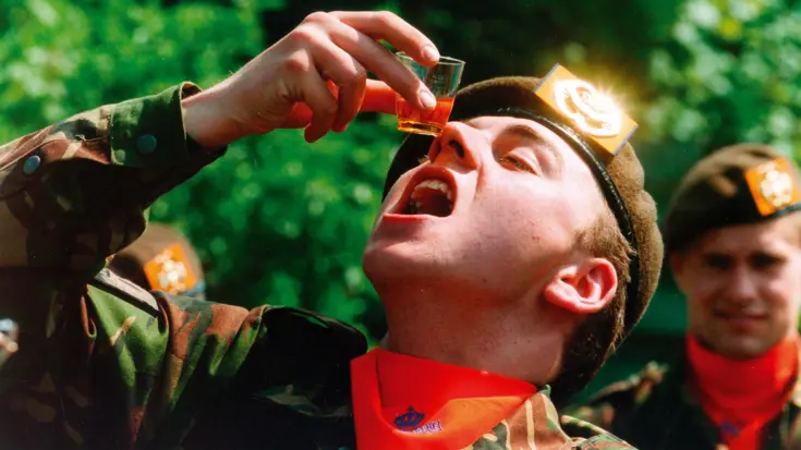 Een militair drinkt  drank uit een shotglaasje.