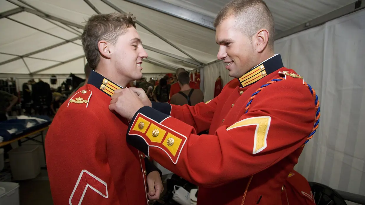 Militairen helpen elkaar bij aantrekken ceremonieel tenue Garderegiment Prinses Irene.