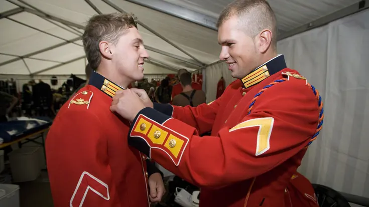 Militairen helpen elkaar bij aantrekken ceremonieel tenue Garderegiment Prinses Irene.