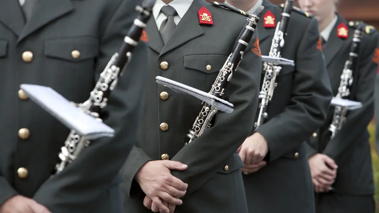 Militairen van de kapel houden een klarinet vast.