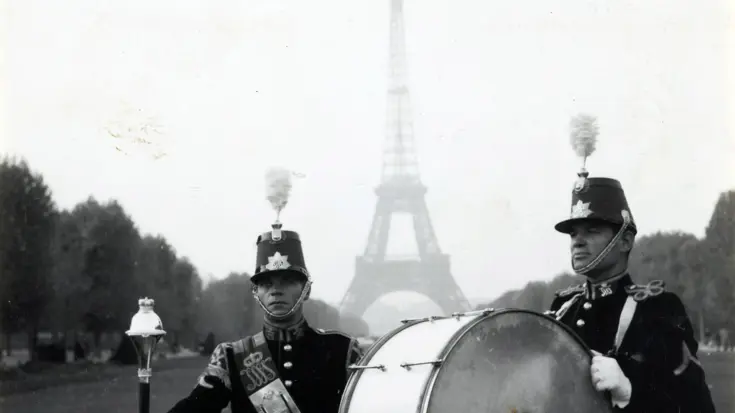 Zwart-witfoto van 2 militaire muzikanten voor de Eiffeltoren.