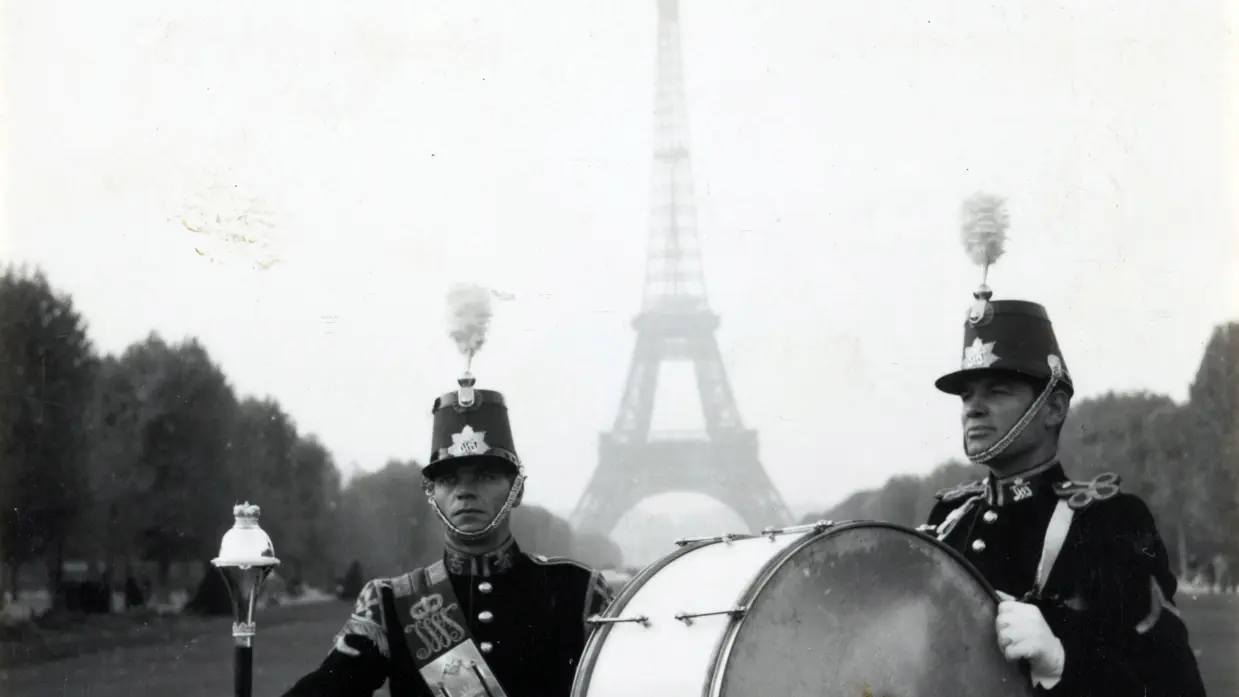 Zwart-witfoto van 2 militaire muzikanten voor de Eiffeltoren.