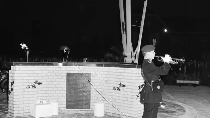 Militair speelt trompet voor monument.