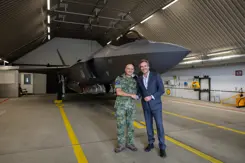Commandant Lucht en Ruimtestrijdkrachten luitenant-generaal André Steur en KLM Executive Vice President Flight Operations Eimert Bult geven elkaar een hand staande voor een F-35.