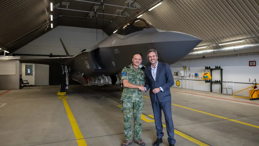 Commandant Lucht en Ruimtestrijdkrachten luitenant-generaal André Steur en KLM Executive Vice President Flight Operations Eimert Bult geven elkaar een hand staande voor een F-35.