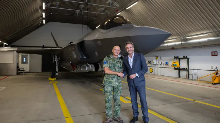 Commandant Lucht en Ruimtestrijdkrachten luitenant-generaal André Steur en KLM Executive Vice President Flight Operations Eimert Bult geven elkaar een hand staande voor een F-35.