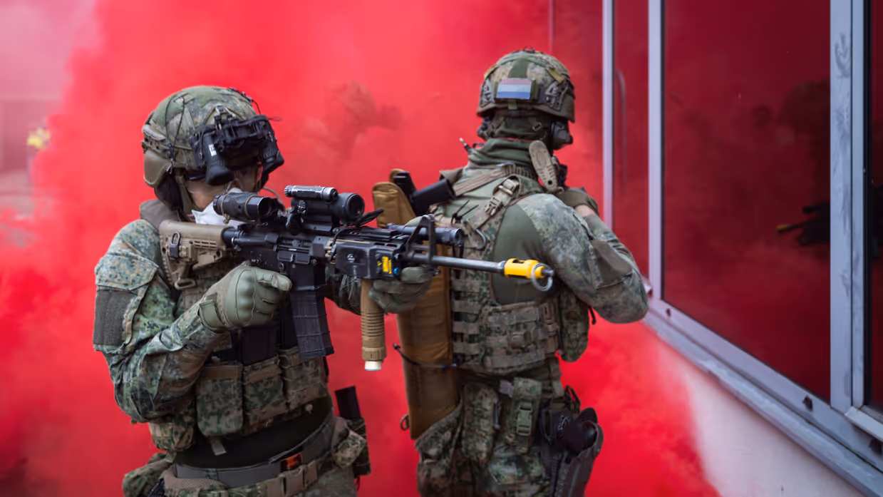 Militairen onder rookgordijn klaar om gebouw binnen te gaan.