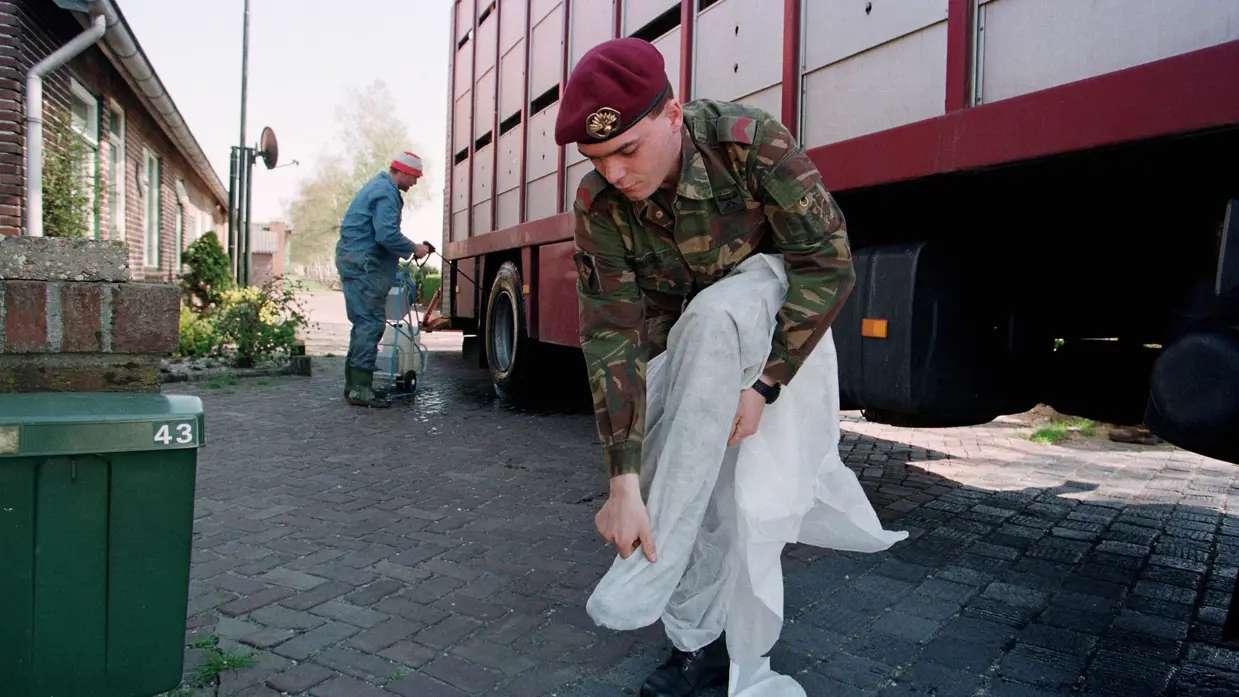 Een militair trekt beschermende kleding aan tijdens de Varkenspestcrisis (Operatie Knor) 1997.