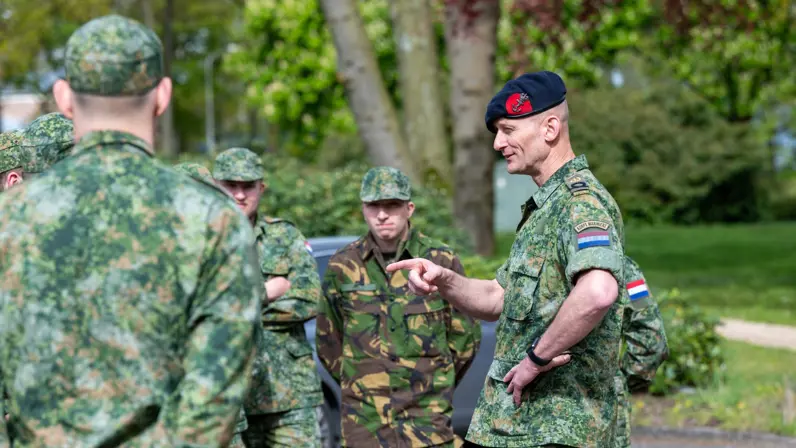 Groepje militairen luistert naar andere militair die spreekt.