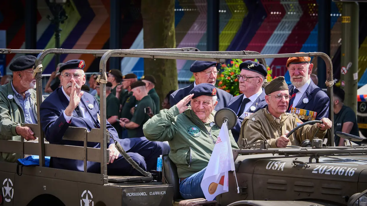 Veteranen salueren vanuit een jeep naar het publiek