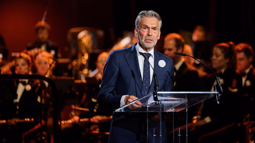 Premier Schoof spreekt de aanwezigen in de Koninklijke Schouwburg toe door een microfoon.