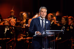 Premier Schoof spreekt de aanwezigen in de Koninklijke Schouwburg toe door een microfoon.