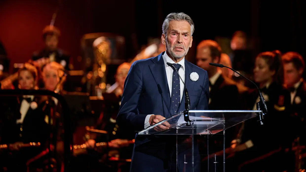 Premier Schoof spreekt de aanwezigen in de Koninklijke Schouwburg toe door een microfoon.
