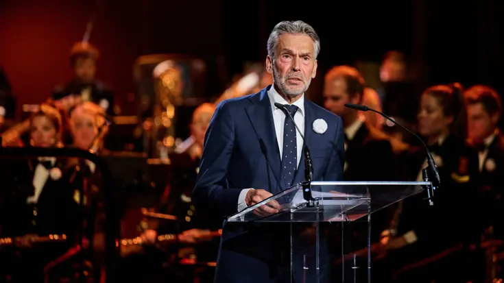 Premier Schoof spreekt de aanwezigen in de Koninklijke Schouwburg toe door een microfoon.