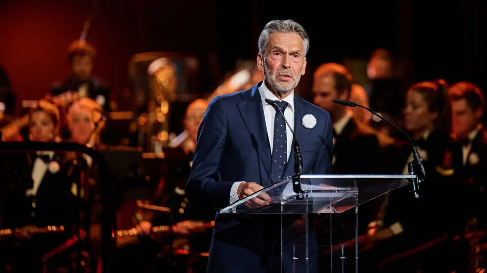 Premier Schoof spreekt de aanwezigen in de Koninklijke Schouwburg toe door een microfoon.