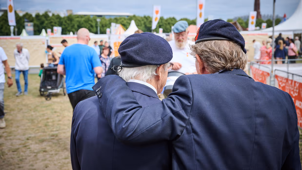 Twee veteranen met hun armen om elkaar op het Malieveld in Den Haag.