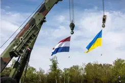 De vlaggen van Nederland en Oekraïne hangen aan een kraan. 