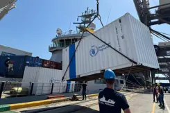 Een witte container met World Food Programme in blauw erop wordt aan land gezet.