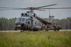 Militairen brengen een militair op een brancard naar een helikopter.