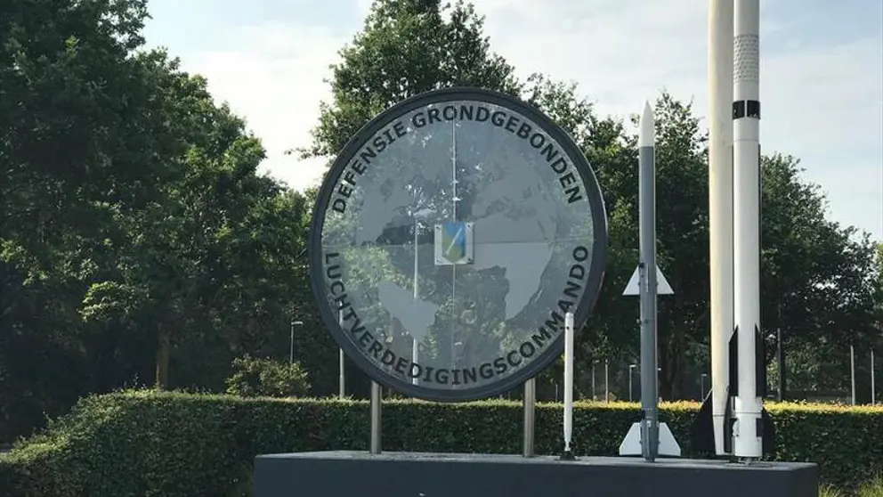 Logo Defensiegebonden Luchtverdedigingscommando, met daarnaast twee raketten