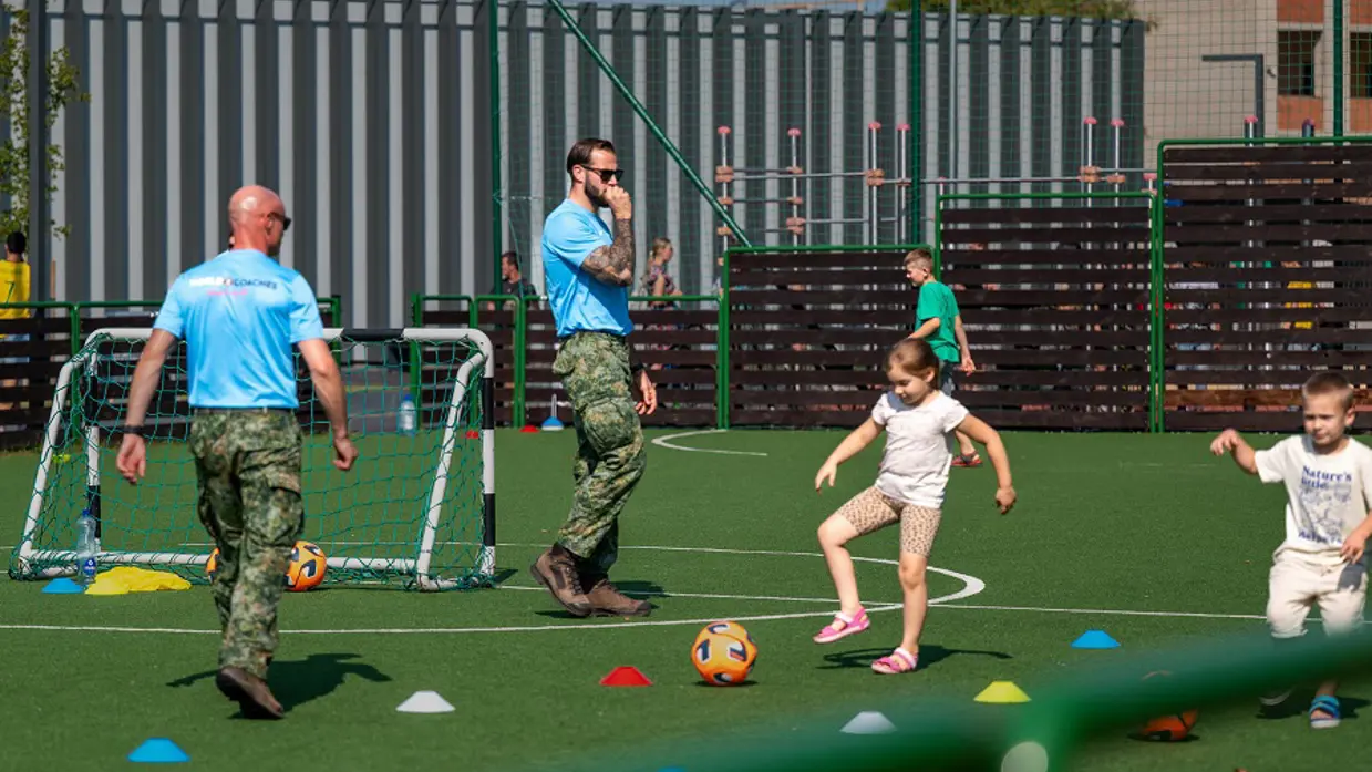 Militairen voetballen met kinderen.