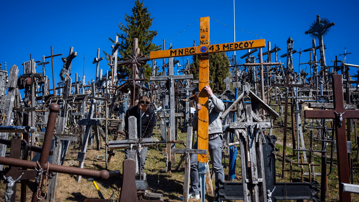 Twee mannen plaatsen een kruis tussen honderden kruizen