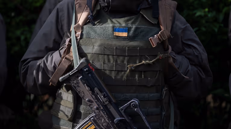 Militair met scherfvest, daarop een Oekraïens vlaggetje.