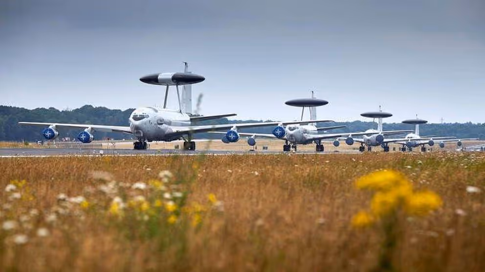 4 Awacs-toestellen op de landingsbaan met bloemetjes op de voorgrond.
