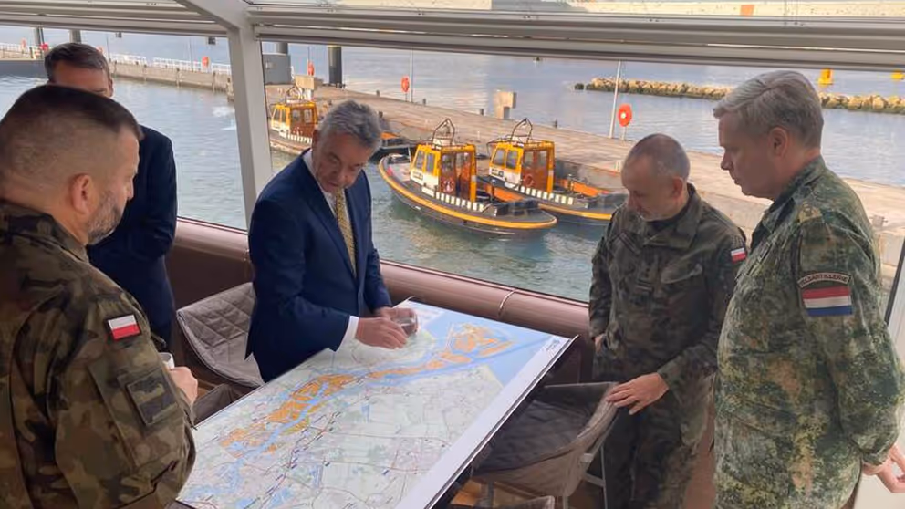 Mannen staan om een landkaart heen.