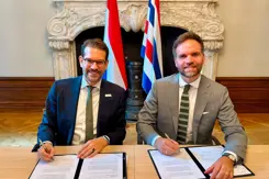 Twee mannen zitten achter een tafel en ondertekenen een formulier.