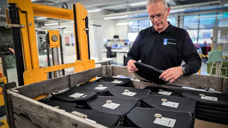 Bert staat achter een bak ballistische platen en doet een visuele inspectie