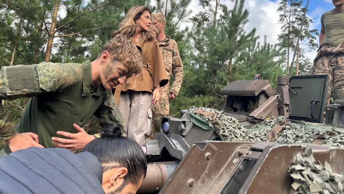 Dilan Yesilgöz tussen militairen bovenop militair voertuig. 